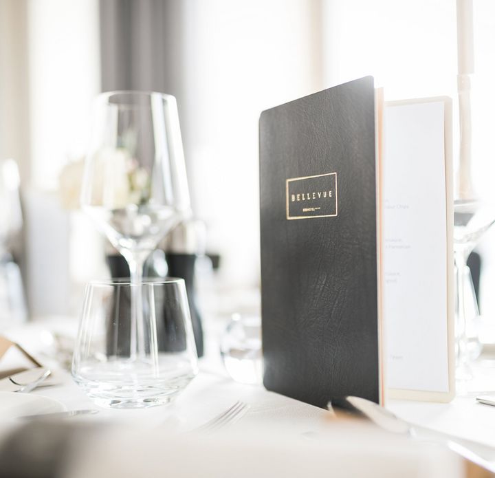 Elegantly set restaurant table with Seehotel Bellevue's menu card
